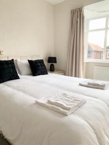 a white bed with two towels on top of it at Immaculate 3-Bed Travel nest unavailable in Manchester