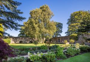 a garden with a stone wall and trees at Farlam Hall Hotel & Restaurant in Brampton