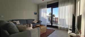 a living room with a gray couch and a television at Arenas de Doñana amplio apartamento frente del mar in Sanlúcar de Barrameda