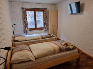 2 camas en una habitación con ventana en Le Catogne en Orsières