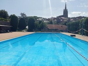una gran piscina con una iglesia en el fondo en CAMPING VERT LAVANDE en Belmont-sur-Rance