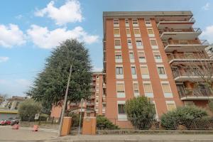 een hoog bakstenen gebouw met een boom ervoor bij SweetHomeSaronno-A 20 minuti da Milano in Saronno