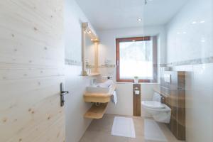 a white bathroom with a sink and a toilet at Landhaus Sunseitn in Ramsau am Dachstein
