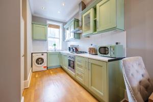 una cucina con armadi verdi e una lavatrice/asciugatrice di Large 1 Bedroom in Center of London a Londra