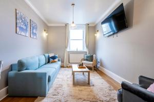 a living room with a blue couch and a tv at Large 1 Bedroom in Center of London in London