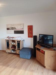 a living room with a tv and a table with a stool at Ferienhaus Häusler in Sankt Erhard