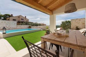 a patio with a wooden table and a swimming pool at Villa Santina by Briskva in Višnjan