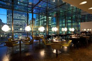 a restaurant with tables and chairs and a view of the city at Large Canary Wharf 2 Bed Apartment with High Rise view in London