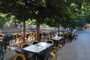 una cafetería al aire libre con mesas, sillas y árboles en APARTAMENTO NEVADA en Pinos Genil