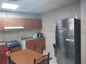 uma cozinha com um frigorífico de aço inoxidável e uma mesa em Pristine Private Bedroom in Dubai With Private Bathroom em Dubai