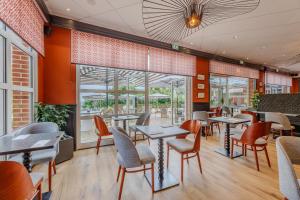 a restaurant with tables and chairs and windows at Dormy House in Étretat