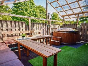 eine Terrasse mit Holzbänken und einem Whirlpool in der Unterkunft Trommeļa brīvdienu mājiņas-kempings in Melnsils