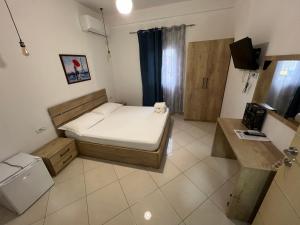 Habitación pequeña con cama y escritorio. en Hotel Apostoli en Përmet