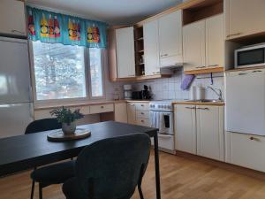 una cocina con armarios blancos y una mesa con sillas. en Home Apartment Haukipudas en Oulu