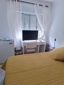 een slaapkamer met een bed en een bureau met een computer bij Quarto Salvador in Laranjeira