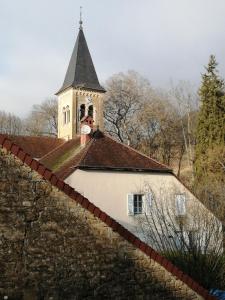 eine Kirche mit einem Uhrturm auf einer Mauer in der Unterkunft A La Halte Des Gorges in Nevy-sur-Seille