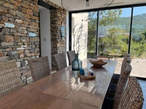 mesa de comedor con sillas y pared de piedra en Le Domaine du Cade-Gîtes d'exception 4étoiles "La Villa du Cade", en Cazevieille