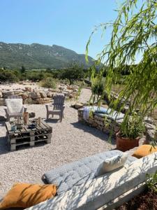 a couch and chairs sitting on a gravel patio at Le Domaine du Cade-Gîtes d'exception 4étoiles "La Villa du Cade" in Cazevieille