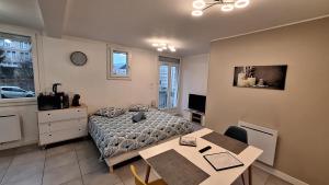 a bedroom with a bed and a table in it at Studio Cosy avec balcon et garage privé in Le Mans