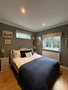 een slaapkamer met een groot bed en 2 ramen bij The Hen House in Chichester