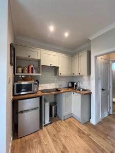 a kitchen with white cabinets and a microwave at The Hen House in Chichester +29 photos