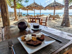 stół z talerzem jedzenia na plaży w obiekcie Bahati Villa w mieście Kiwengwa
