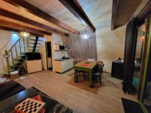 a room with a table and a kitchen and stairs at Cabana Vânătorilor A Frame Green in Văliug