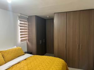 1 dormitorio con cama amarilla y armarios de madera en apartamento privado en Bogotá