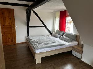 Bett in einem Zimmer mit rotem Fenster in der Unterkunft Pension Zum Fäßchen in Naumburg