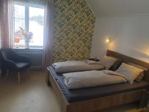 um quarto com uma cama, uma cadeira e uma janela em Bed & Breakfast de Jager em Strömsbruk