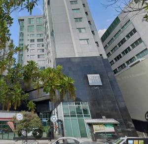 um edifício alto com árvores em frente em Ap loft Belvedere fronte shopping BH em Belo Horizonte