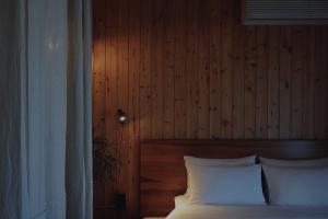a bedroom with a bed with white pillows and a wooden wall at At corner resort & garden in Jeju