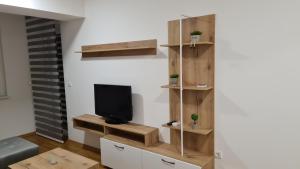 a living room with a tv and wooden shelves at Apartment Leona in Skopje
