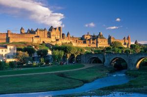 a castle on a hill with a bridge and a river at La maison de Mona in Carcassonne