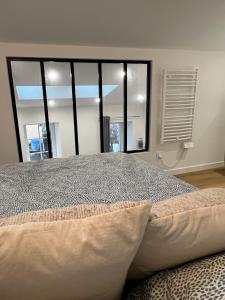 sypialnia z dużym łóżkiem i dużym oknem w obiekcie Petite maison de ville avec mezzanine w mieście Ruelle-sur-Touvre