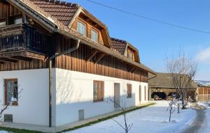 Casa de madera grande con nieve en el suelo en Ferienwohnung Friedlhof en Feldkirchen in Kärnten