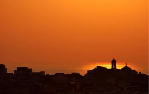 eine Silhouette einer Stadt mit einem Uhrturm bei Sonnenuntergang in der Unterkunft Cozy Home In Santa Croce Camerina in Santa Croce Camerina