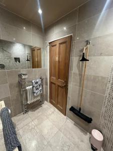 a bathroom with a shower and a wooden door at Airthrey Cottage in Bridge of Allan