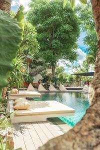 a swimming pool with lounge chairs and trees at Savanna Ubud in Ubud