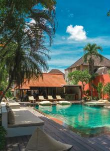 a resort swimming pool with chairs and palm trees at Savanna Ubud in Ubud