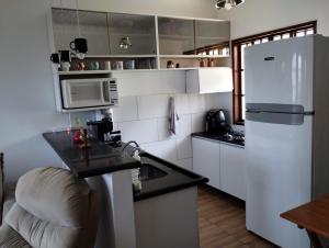a small kitchen with a white refrigerator and a counter at Casa 2 qtos, sendo suíte com cama Queen ar condicionado in Guapimirim