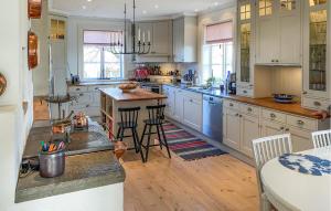 una cocina con armarios blancos y una isla con taburetes. en 3 Bedroom Amazing Home In Borgholm en Borgholm