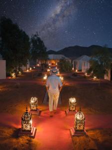 a man walking down a path at night with lights at Erg chebbi Dunes Desert Camp in Merzouga