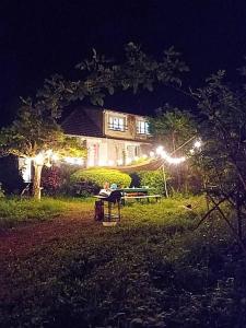 osoba siedząca przy stole piknikowym przed domem w nocy w obiekcie Maison de campagne en cours de rénovation accessible en train w mieście Cravant