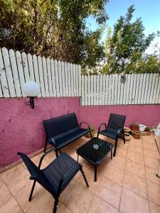 een patio met stoelen, een tafel en een hek bij Ramban Emerald in Haifa