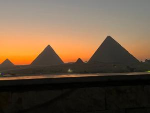 widok na piramidy gizy o zachodzie słońca w obiekcie Imhotep pyramids INN w Kairze