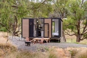 a tiny house in the woods with a table and chairs at The Meadows Tiny House in Macclesfield