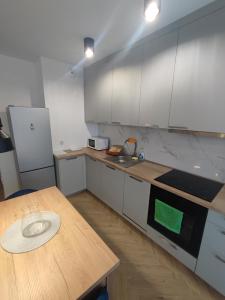 a kitchen with a wooden table and white cabinets at Apartament Czartoryskich House z miejscem postojowym in Puławy