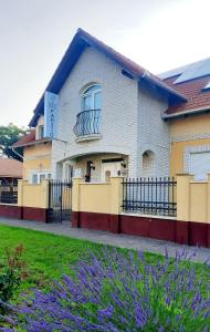 a building with a fence and purple flowers at Sóvirág Termál Panzió in Hajdúnánás