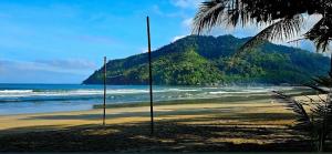 a beach with two poles in the sand and the ocean at Balai Ko - Tent 1 in Locaroc